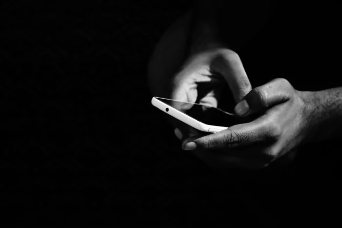 grey scale photo of person using a smartphone